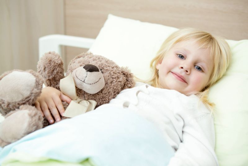 Girl in bed holding stuffed animal