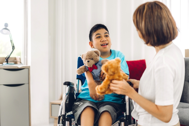 A muscle disease patient is holding a teddy bear