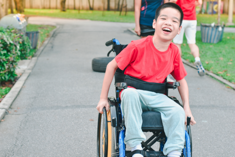 Happy disabled boy a on wheelchair is play and learn in the outdoor park with other people