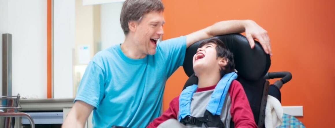 Man and boy in cerebral palsy wheelchair laughing
