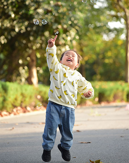 Child jumping to catch bubbles