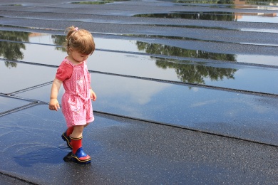 Young girl walking through water puddles